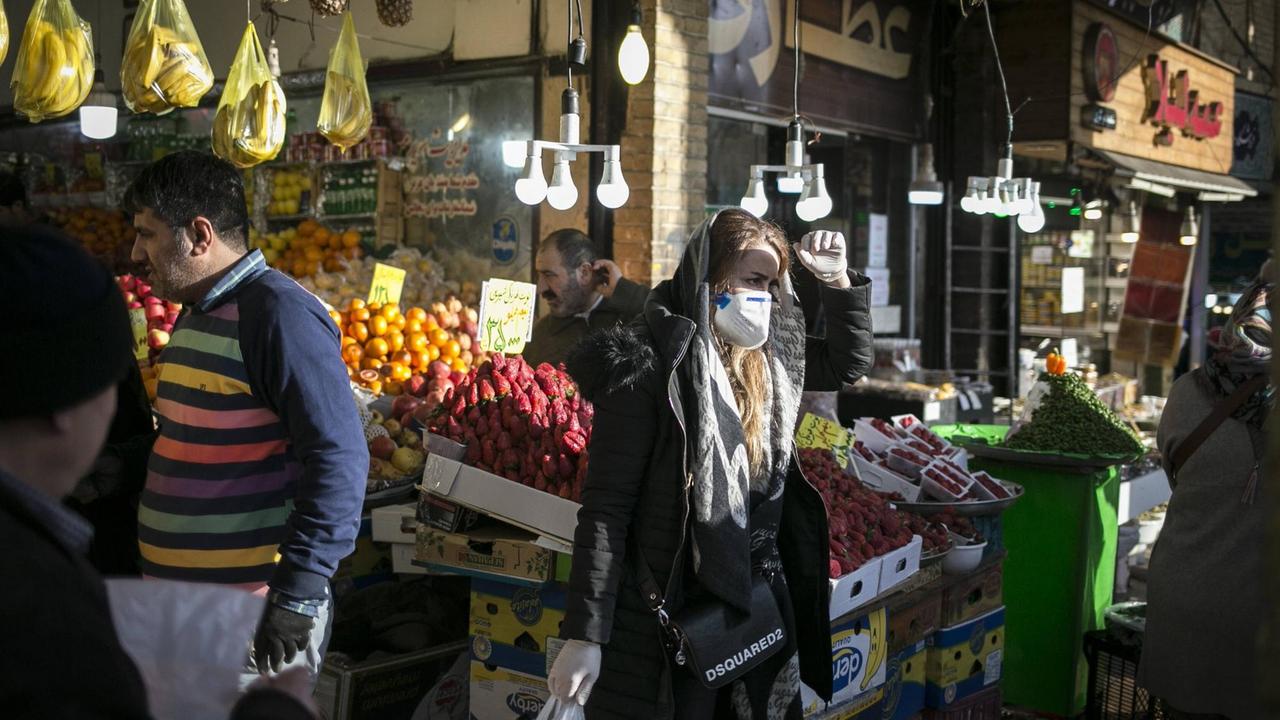 Eine Frau mit Schutzmaske steht auf einem Markt in Teheran. Eine Frau mit Schutzmaske steht auf einem Markt in Teheran.