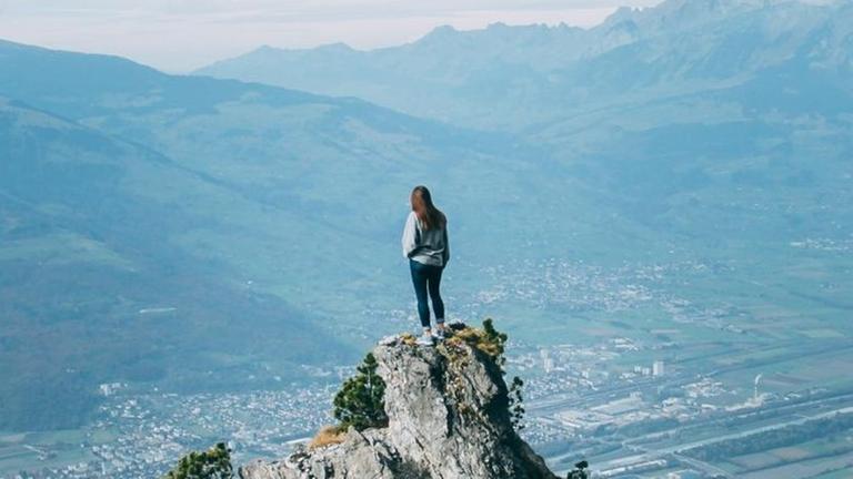 Eine junge Frau steht in Liechtenstein auf dem Fürstensteig und blickt auf die Landschaft unter ihr. Eine junge Frau steht in Liechtenstein auf dem Fürstensteig und blickt auf die Landschaft unter ihr.
