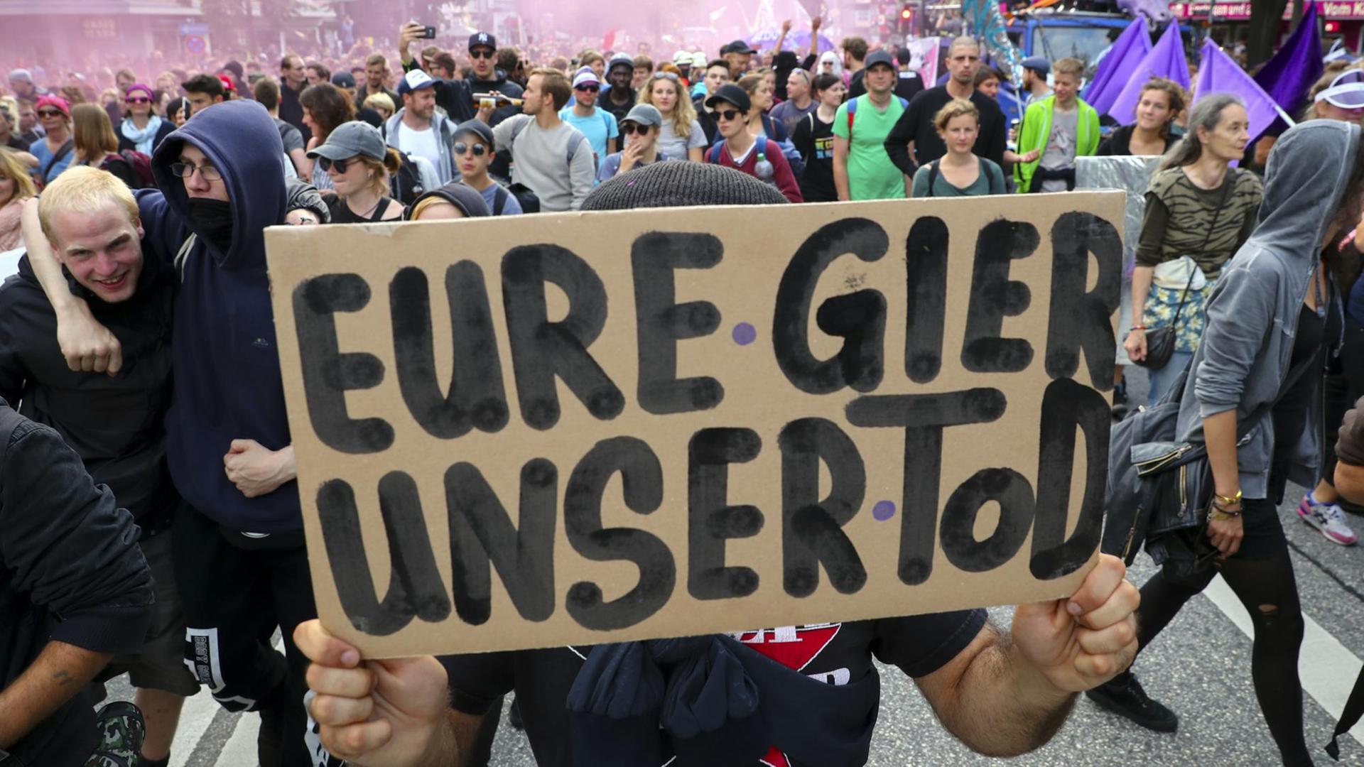 Teilnehmer einer Demonstration gegen den bevorstehenden G20-Gipfel laufen am 05.07.2017 in Hamburg über die Reeperbahn und halten dabei ein Schild mit der Aufschrift "Eure Gier ist unser Tod" in die Höhe. Teilnehmer einer Demonstration gegen den bevorstehenden G20-Gipfel laufen am 05.07.2017 in Hamburg über die Reeperbahn und halten dabei ein Schild mit der Aufschrift "Eure Gier ist unser Tod" in die Höhe.