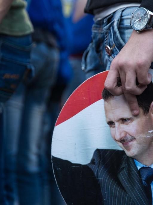 Demonstranten in Latakia bei einer Kundgebung für das Regime Assad, ein Schild mit seinem Konterfei in der Hand