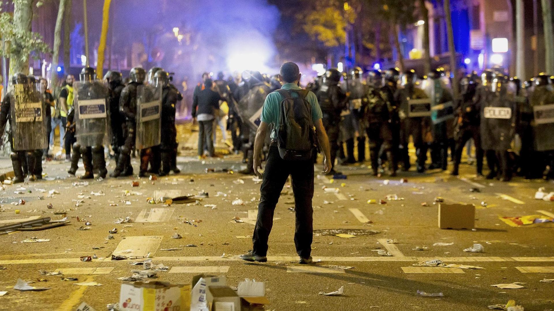 Bei Demonstartionen der Katalonischen Seperatisten am 15. Oktober 2019 in Barcelona steht ein Mann einer Reihe schwer ausgerüsteter Polizisten gegenüber, der Boden ist übersät mit Müll. Bei Demonstartionen der Katalonischen Seperatisten am 15. Oktober 2019 in Barcelona steht ein Mann einer Reihe schwer ausgerüsteter Polizisten gegenüber, der Boden ist übersät mit Müll.