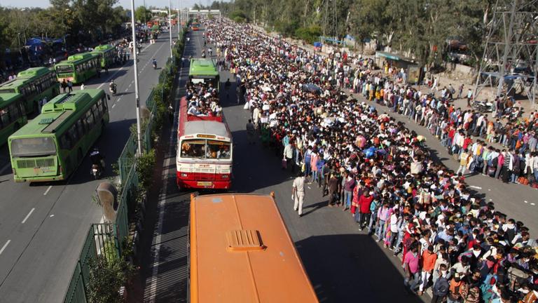 27.03.2020, Indien, Neu Delhi: Tausende Wanderarbeiter und Tagelöhner warten auf Busse, die sie von der Hauptstadt aus in ihre Heimatdörfer bringen sollen. 