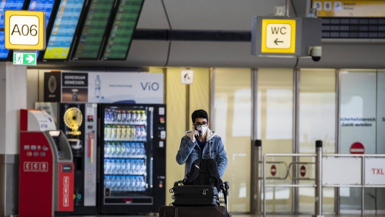 Ein Passagier ein einem sonst leeren Flughafen Tegel mit Munschutzmaske in Berlin am 19. Maerz 2020. Ein Passagier ein einem sonst leeren Flughafen Tegel mit Munschutzmaske in Berlin am 19. Maerz 2020.