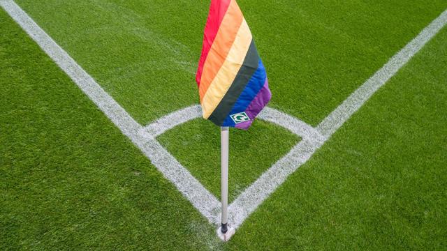 Eine Regenbogen-Eckfahne steckt in einer Ecke des Fußballfeldes.
