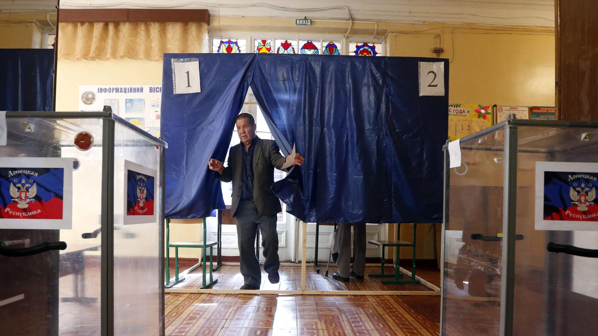 Ein Man steht zwischen zwei Wahlurnen.