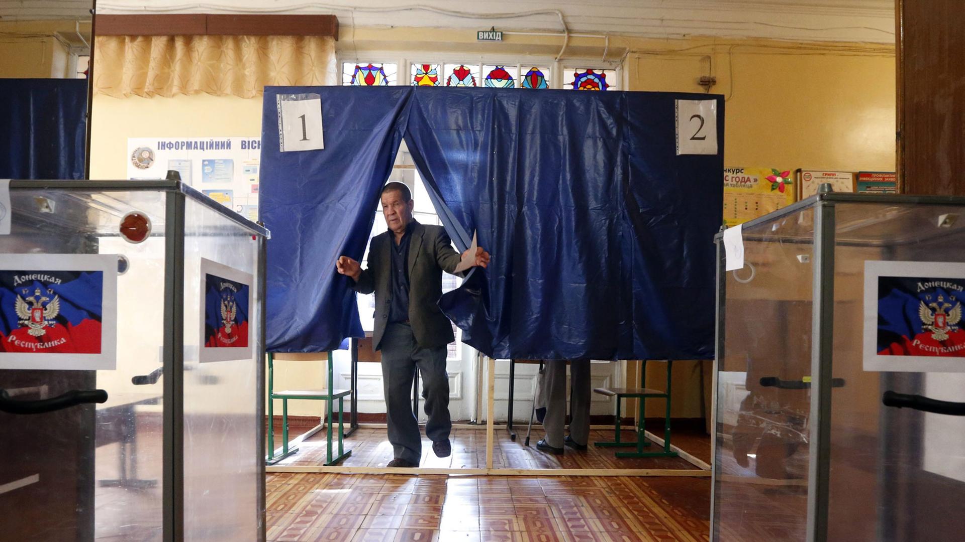 Ein Man steht zwischen zwei Wahlurnen. Ein Man steht zwischen zwei Wahlurnen.