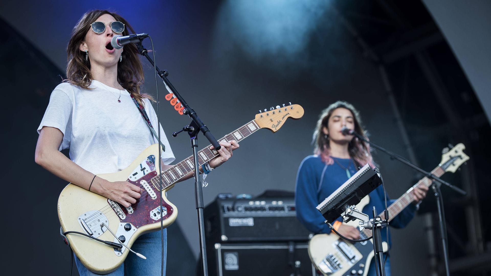 Zwei Musikerinnen spielen auf einer Bühne E-Gitarre und E-Bass Zwei Musikerinnen spielen auf einer Bühne E-Gitarre und E-Bass