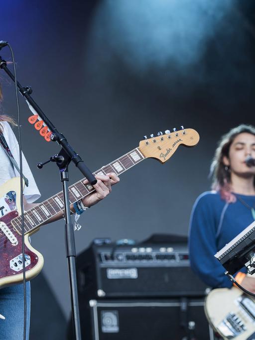 Zwei Musikerinnen spielen auf einer Bühne E-Gitarre und E-Bass