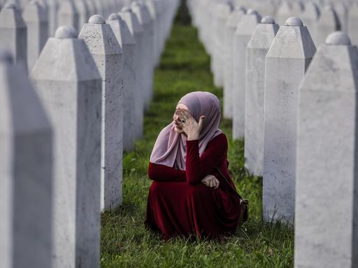 Eine bosnisch-muslimische Frau weint zwischen den Gräbern ihres Vaters, zweier Großväter und anderer enger Verwandter, auf dem Friedhof in Potocari in der Nähe von Srebrenica, Bosnien und Herzegowina.