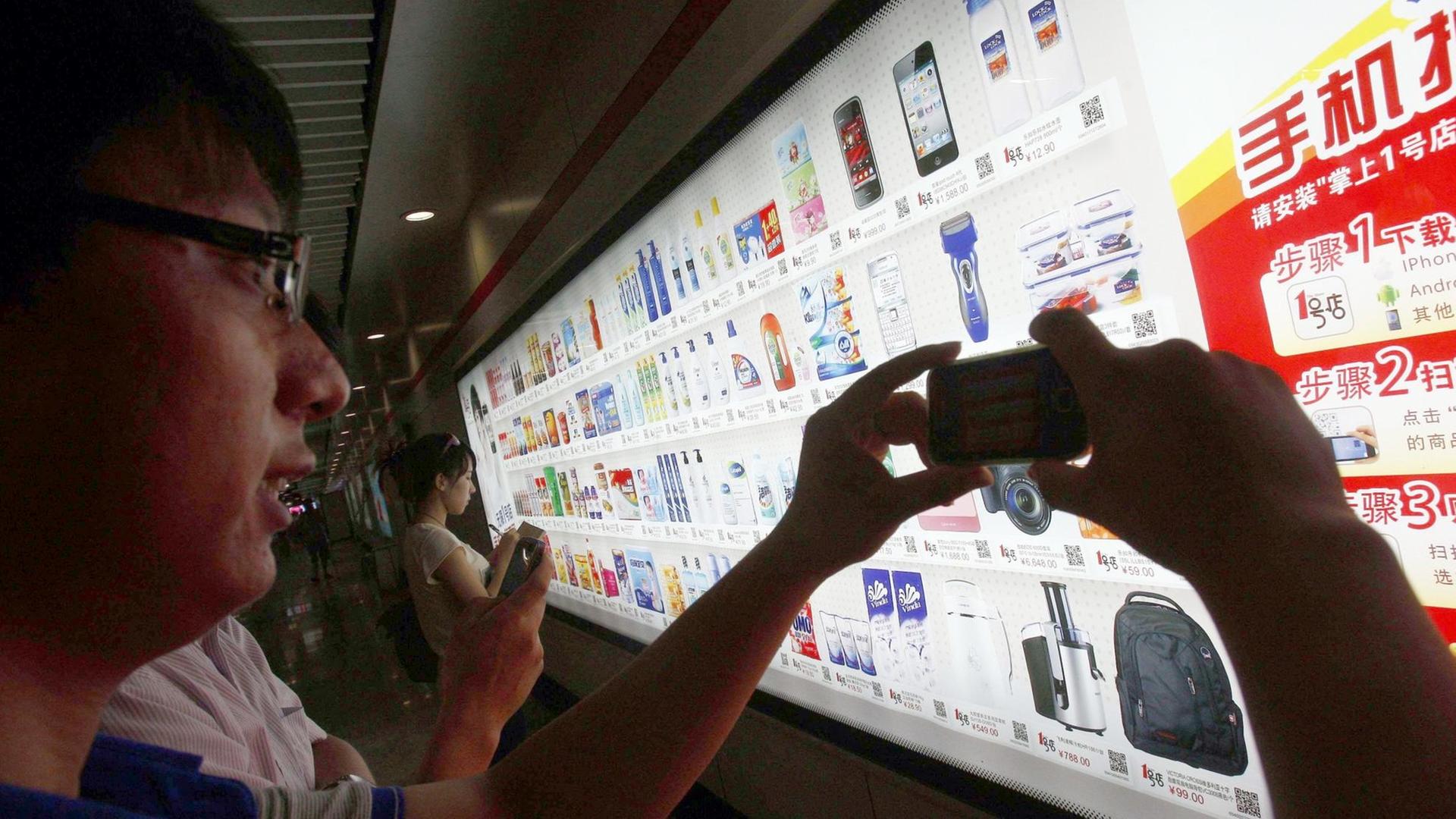 Ein Fahrgast kauft bei der Fahrt in der U-Bahn virtuell ein und studiert die Angebote im Supermarkt. Ein Fahrgast kauft bei der Fahrt in der U-Bahn virtuell ein und studiert die Angebote im Supermarkt.