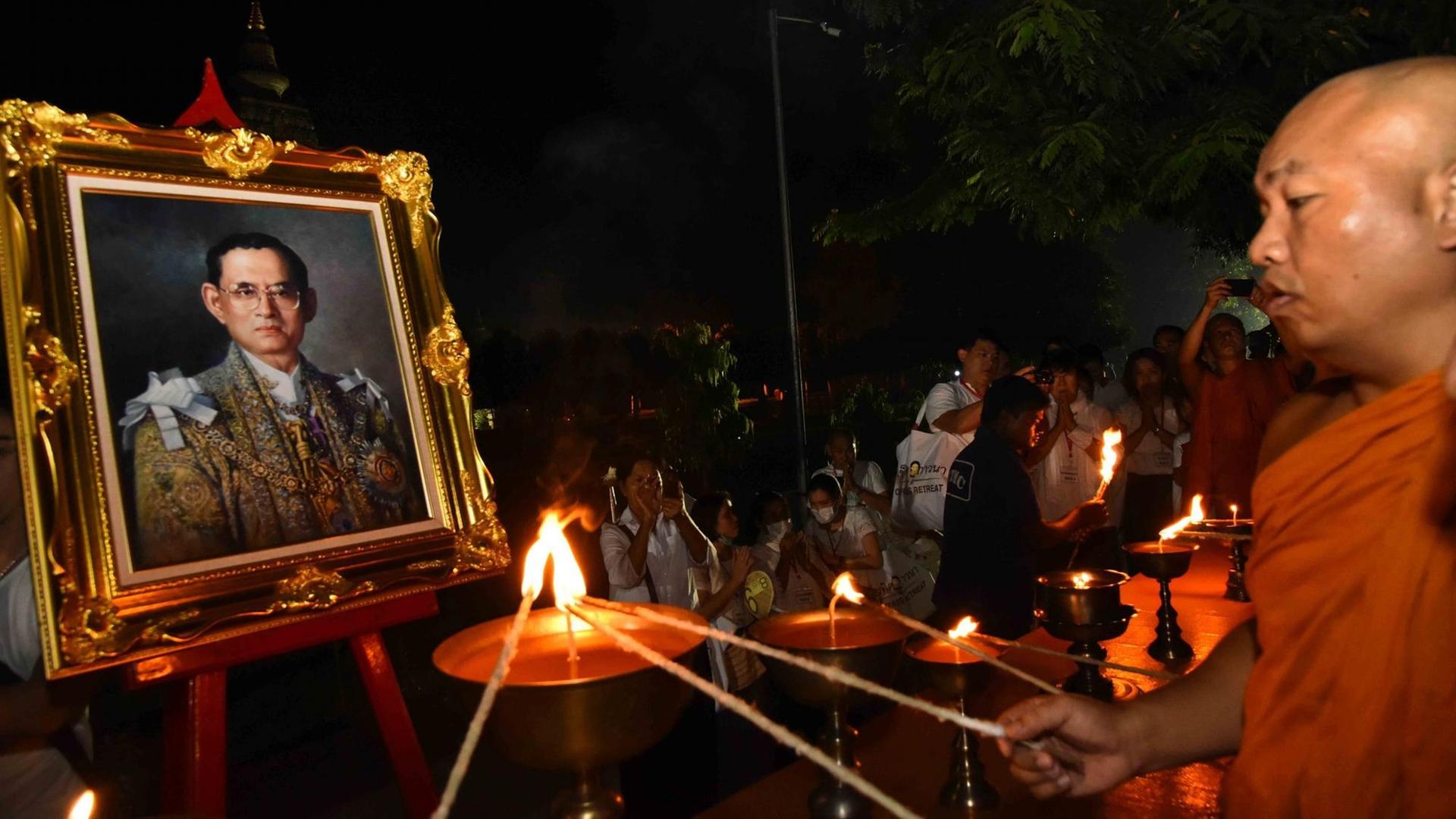 Ein buddhistischer Mönch entzündet eine Kerze in Gedenken an den verstorbenen König Bhumibol Ein buddhistischer Mönch entzündet eine Kerze in Gedenken an den verstorbenen König Bhumibol
