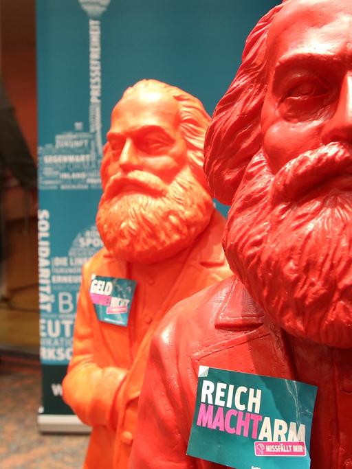 Rote Plastikfiguren von Karl Marx mit dem Slogan "Reich macht arm - Missfällt mir" sind im Februar 2014 vor dem Bundesparteitag der Partei Die Linke in Hamburg zu sehen.