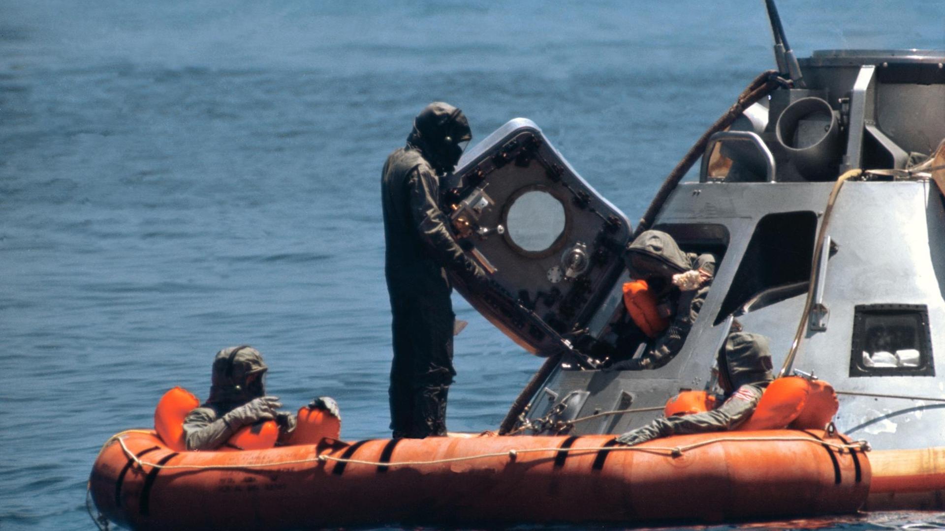 Der dritte Astronaut der Apollo 11-Mission steigt am 24. Juli 1969 aus der "Columbia", die auf dem Pazifik gewassert ist. Alle tragen spezielle Anzüge. Der dritte Astronaut der Apollo 11-Mission steigt am 24. Juli 1969 aus der "Columbia", die auf dem Pazifik gewassert ist. Alle tragen spezielle Anzüge.