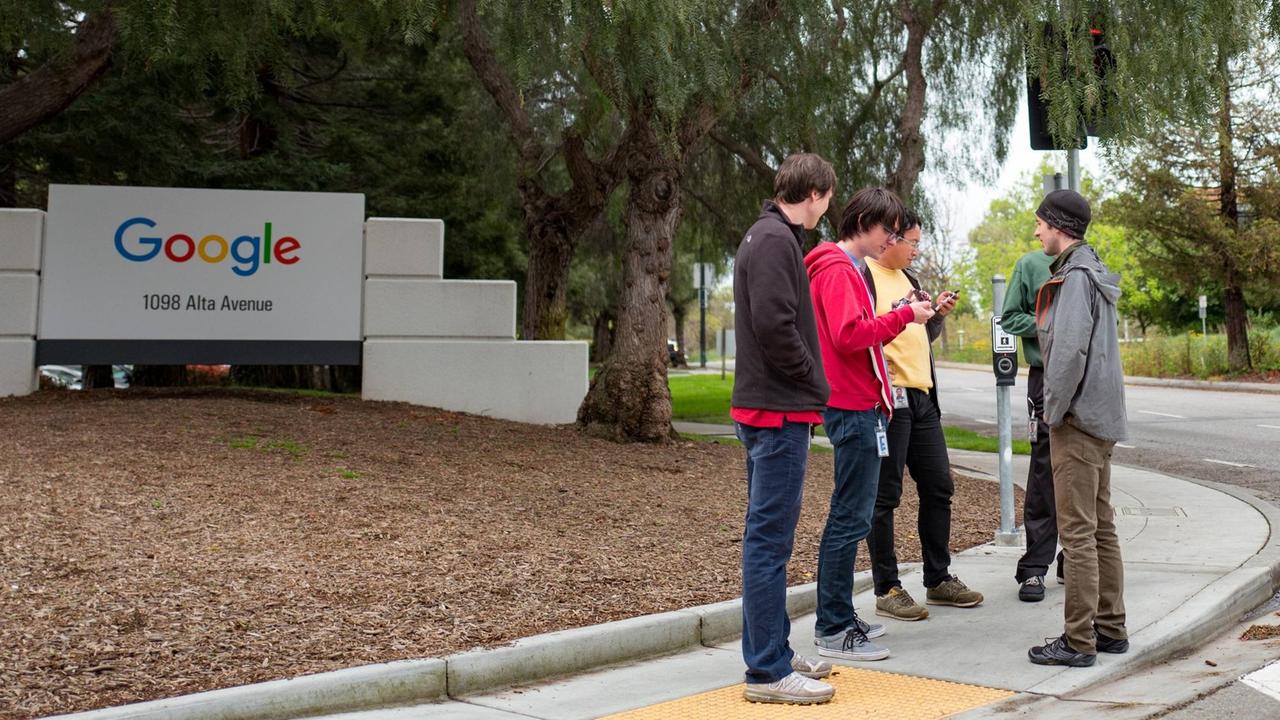 Eine Gruppe jugendlicher Mitarbeiter stehen vor dem Eingang von Google im Silicon Valley
