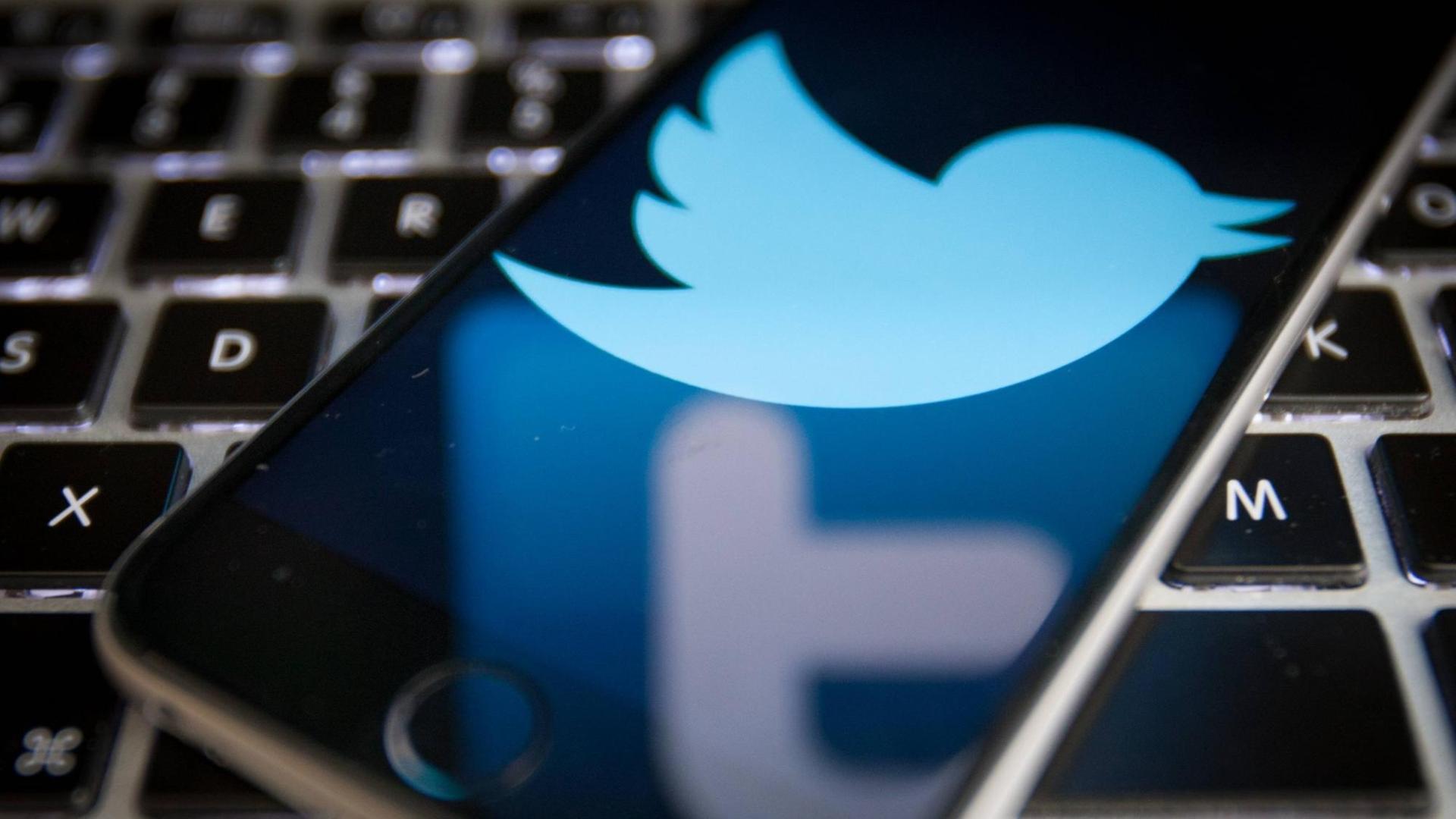 Twitter-Logo auf einem Smartphone, das auf einer Laptoptastatur liegt. Twitter-Logo auf einem Smartphone, das auf einer Laptoptastatur liegt.