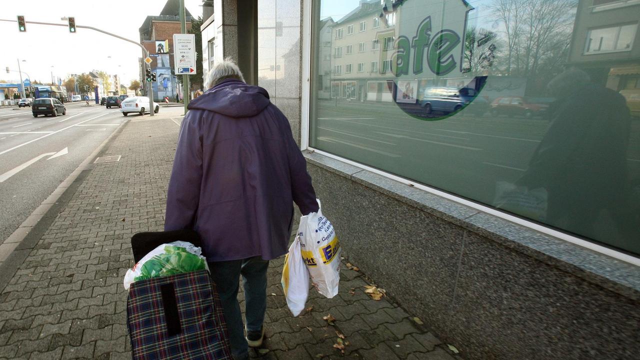 Eine ältere Dame verlässt bepackt mit Tragetaschen und einem gefüllten Trolley die "Kasseler Tafel", in der sie zuvor Lebensmittel bezogen hat. Eine ältere Dame verlässt bepackt mit Tragetaschen und einem gefüllten Trolley die "Kasseler Tafel", in der sie zuvor Lebensmittel bezogen hat.