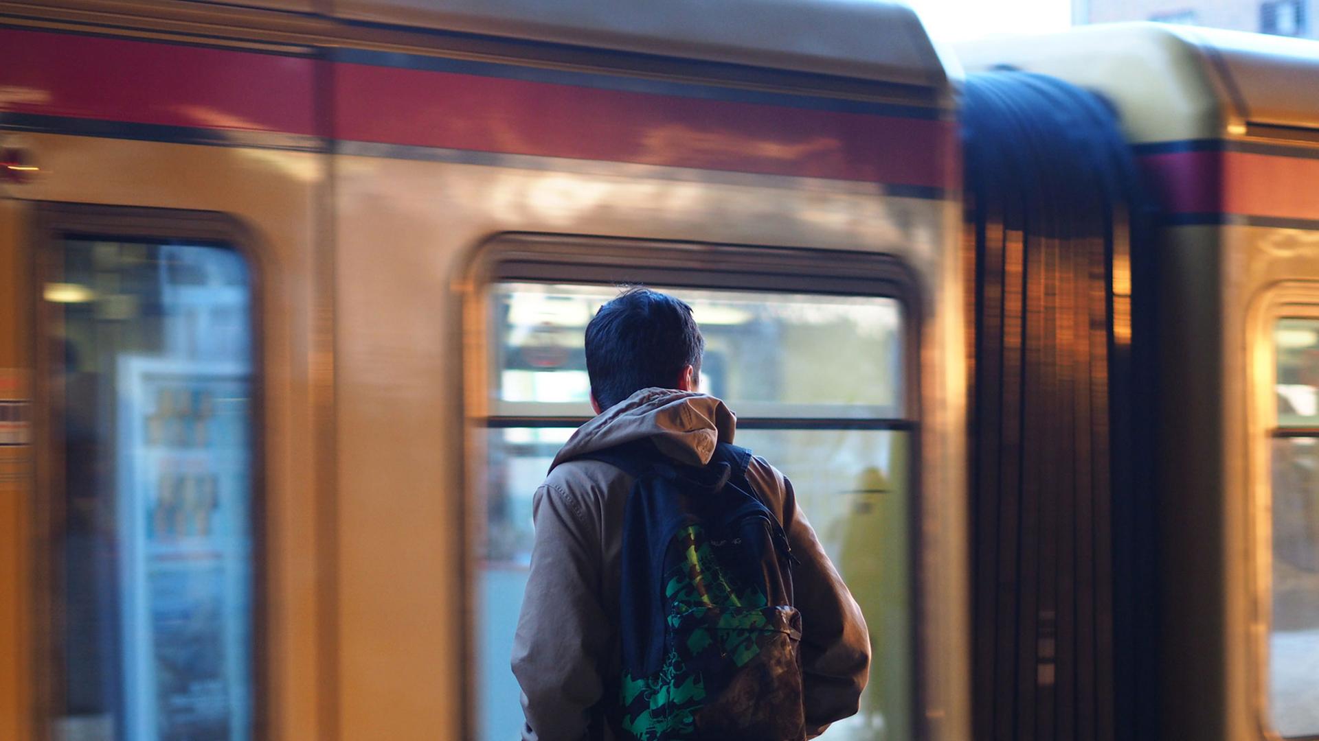 Ein junger Mann mit einem Rucksack steht an der S-Bahn in Berlin.