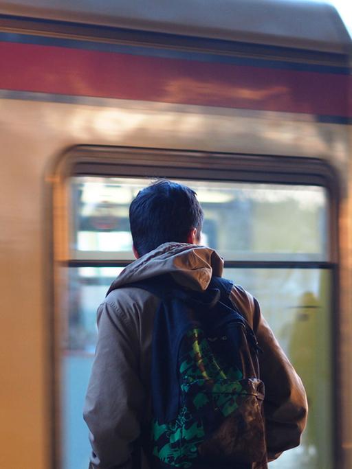 Ein junger Mann mit einem Rucksack steht an der S-Bahn in Berlin.