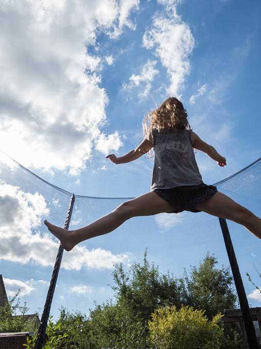 Ein Mädchen springt in einem Garten in Hannover auf einem Trampolin.
