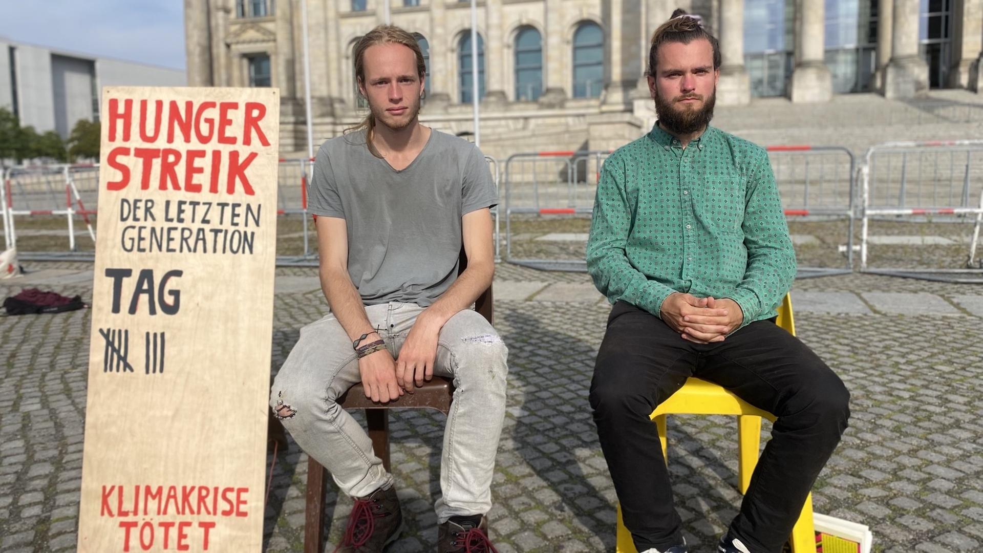 Simon Helmstedt und Jacob Heinze vor einem Schild, auf dem sie die Tage ihres Hungerstreiks zählen.