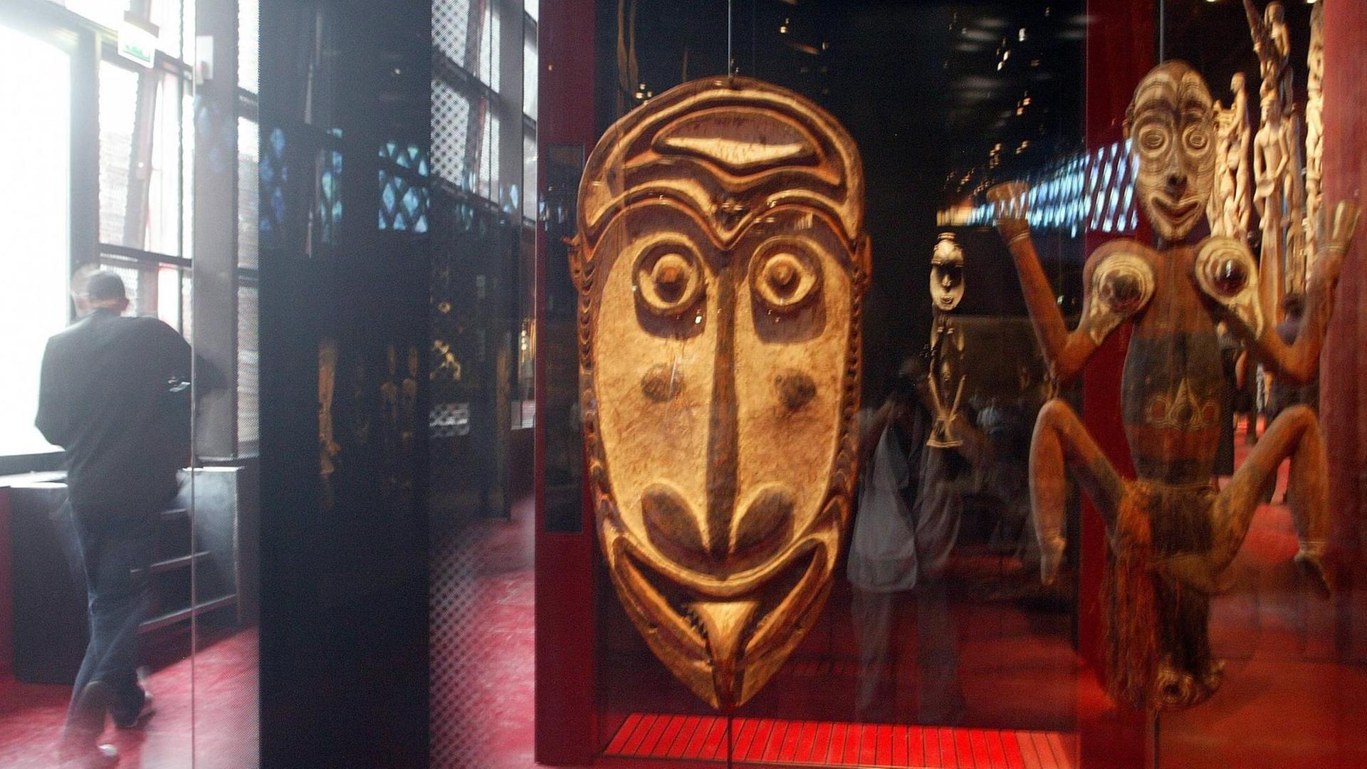 Besucher und aus Holz geschnitzte afrikanische Masken im neuen ethnologischen Museum - Musee du Quai Branly in Paris.