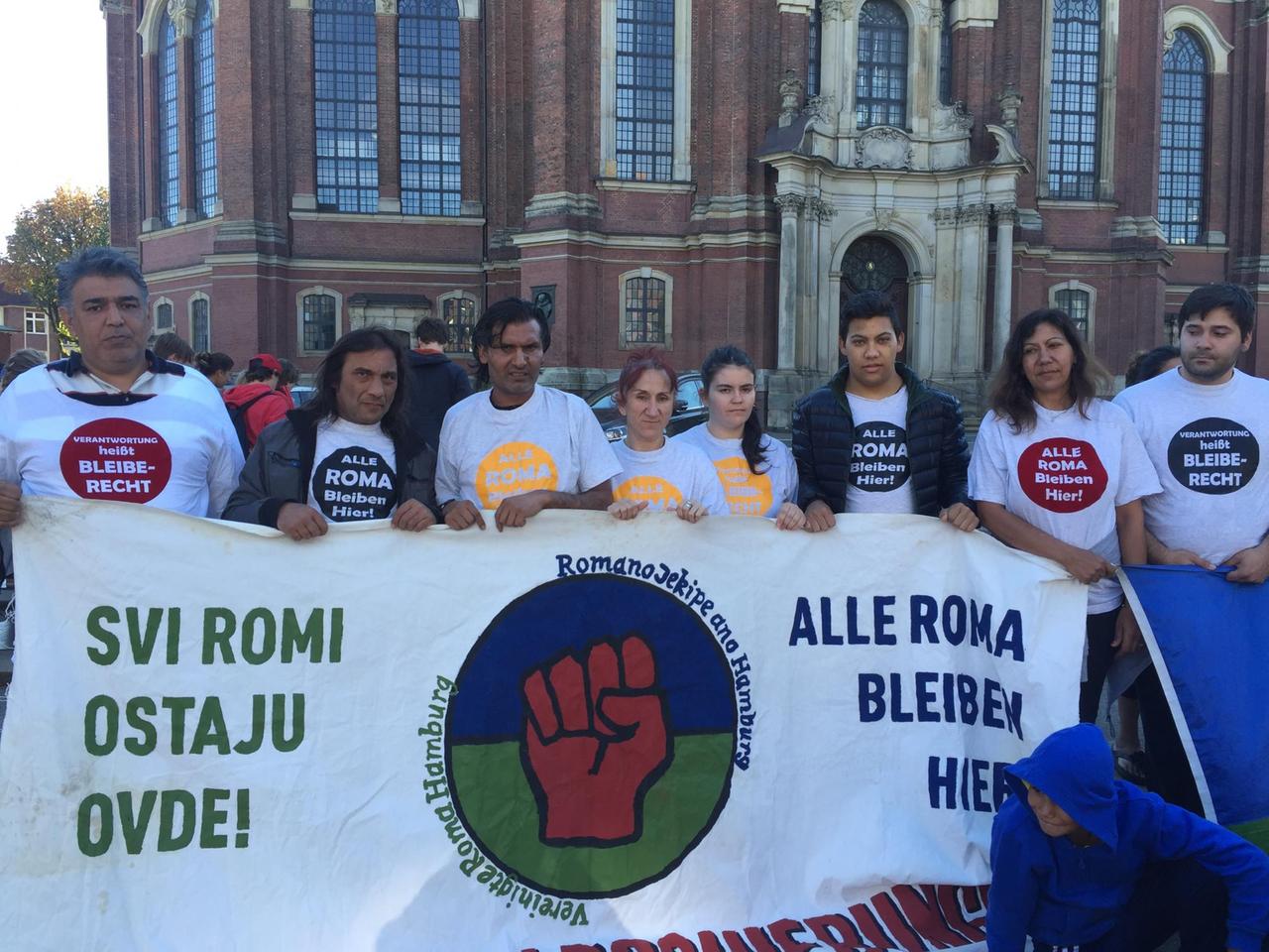 Eine Gruppe von Roma steht mit einem Protestbanner vor dem Hamburger Michel.