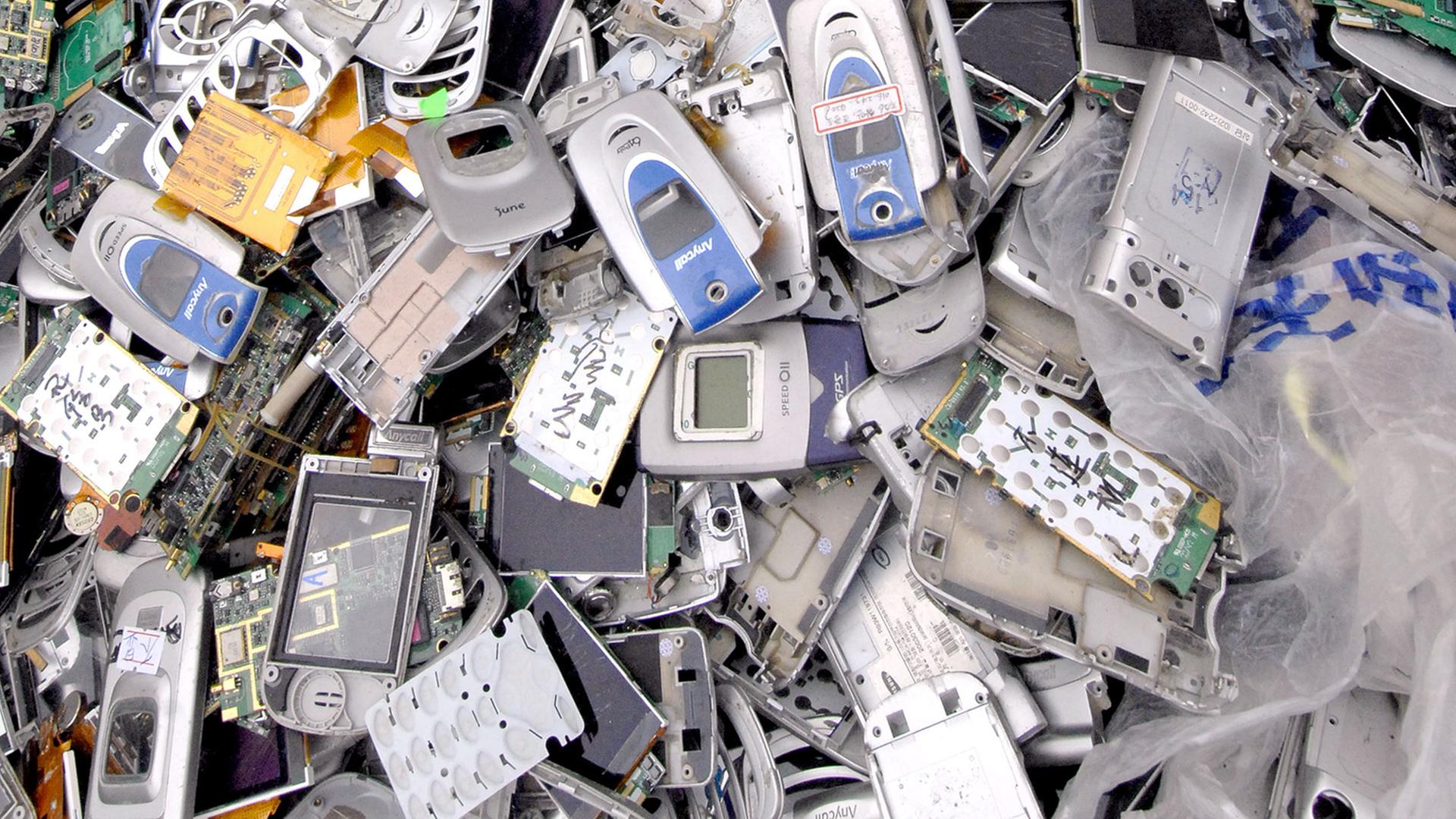 Zu sehen ist ein Müllcontainer mit unzähligen alten Mobiltelefonen. Zu sehen ist ein Müllcontainer mit unzähligen alten Mobiltelefonen.