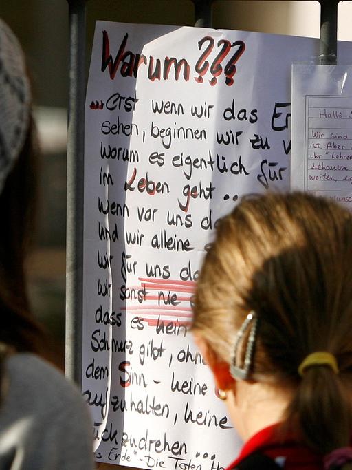 Jugendliche betrachten an einem Schultor einen Zettel mit dem Titel "Warum???"