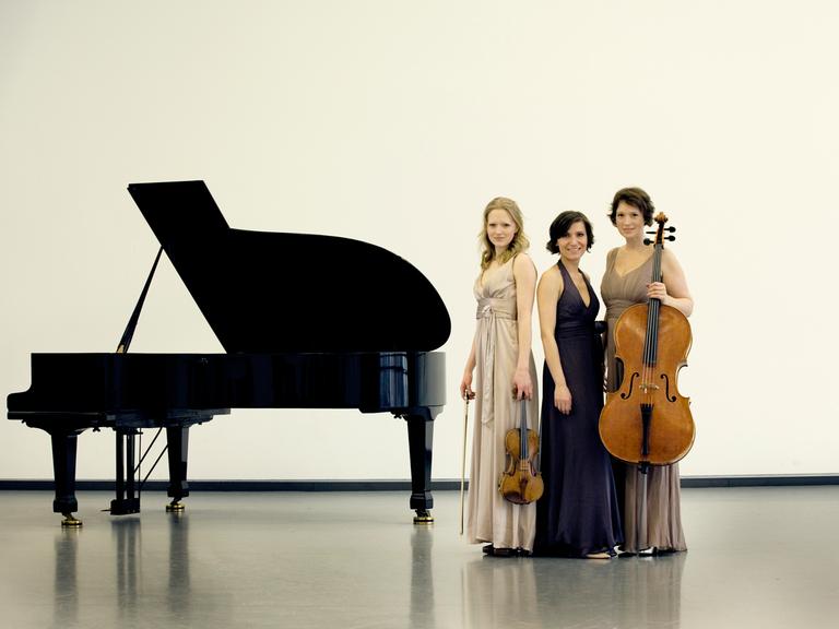 Das Boulanger Trio steht neben einem Klavier.
