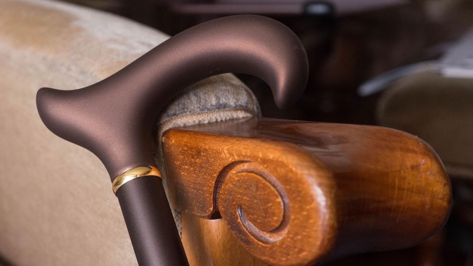 Ein brauner Krückstock lehnt an einem Sessel. Ein brauner Krückstock lehnt an einem Sessel.