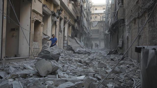 Ein Syrer steht auf einem Haufen Schutt in einem Stadtteil von Aleppo - nach einem Luftangriff.