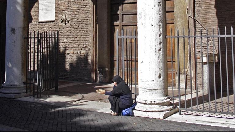 Eine arme Frau bittet vor der Kirche Santa Sabina auf dem Hügel Aventin in Rom um Almosen.