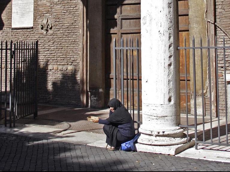 Eine arme Frau bittet vor der Kirche Santa Sabina auf dem Hügel Aventin in Rom um Almosen.