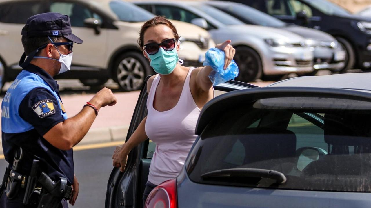 Teneriffa: Eine Frau mit Atemschutzmaske steht neben ihrem Auto und spricht mit einer Polizistin Teneriffa: Eine Frau mit Atemschutzmaske steht neben ihrem Auto und spricht mit einer Polizistin
