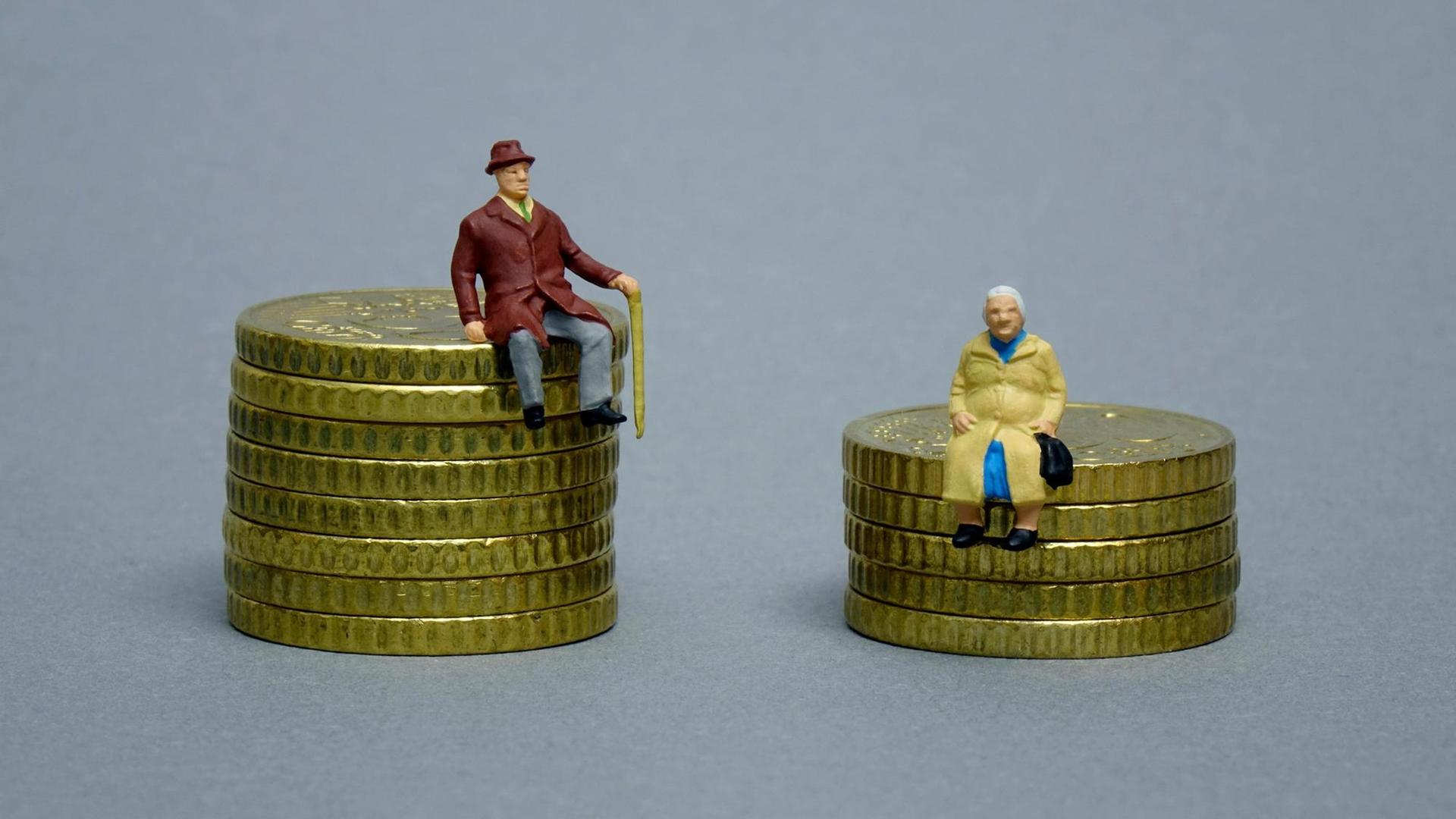 Die Figuren eines Rentners und einer Rentnerin sitzen auf verschieden hohen Geldstapeln. Die Figuren eines Rentners und einer Rentnerin sitzen auf verschieden hohen Geldstapeln.