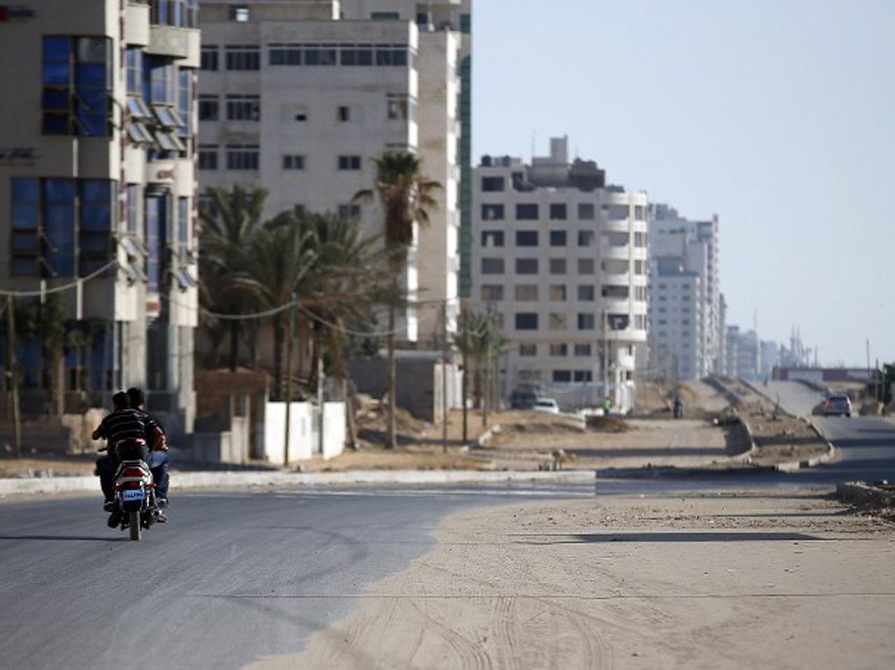 Palästinenser fahren mit einem Motorrad entlang einer ausgestorbenen Straße im Gaza-Streifen. Palästinenser fahren mit einem Motorrad entlang einer ausgestorbenen Straße im Gaza-Streifen.