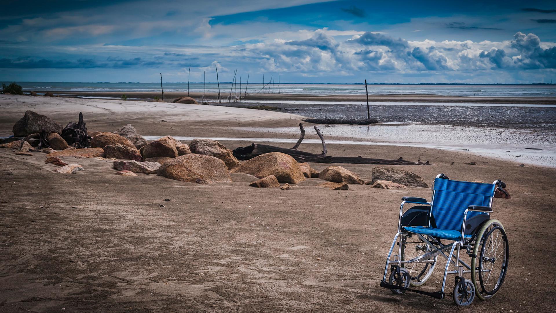 Verliert ein eingeschränktes Leben seinen Wert? Ein blauer Rollstuhl an einem Strand. Verliert ein eingeschränktes Leben seinen Wert? Ein blauer Rollstuhl an einem Strand.