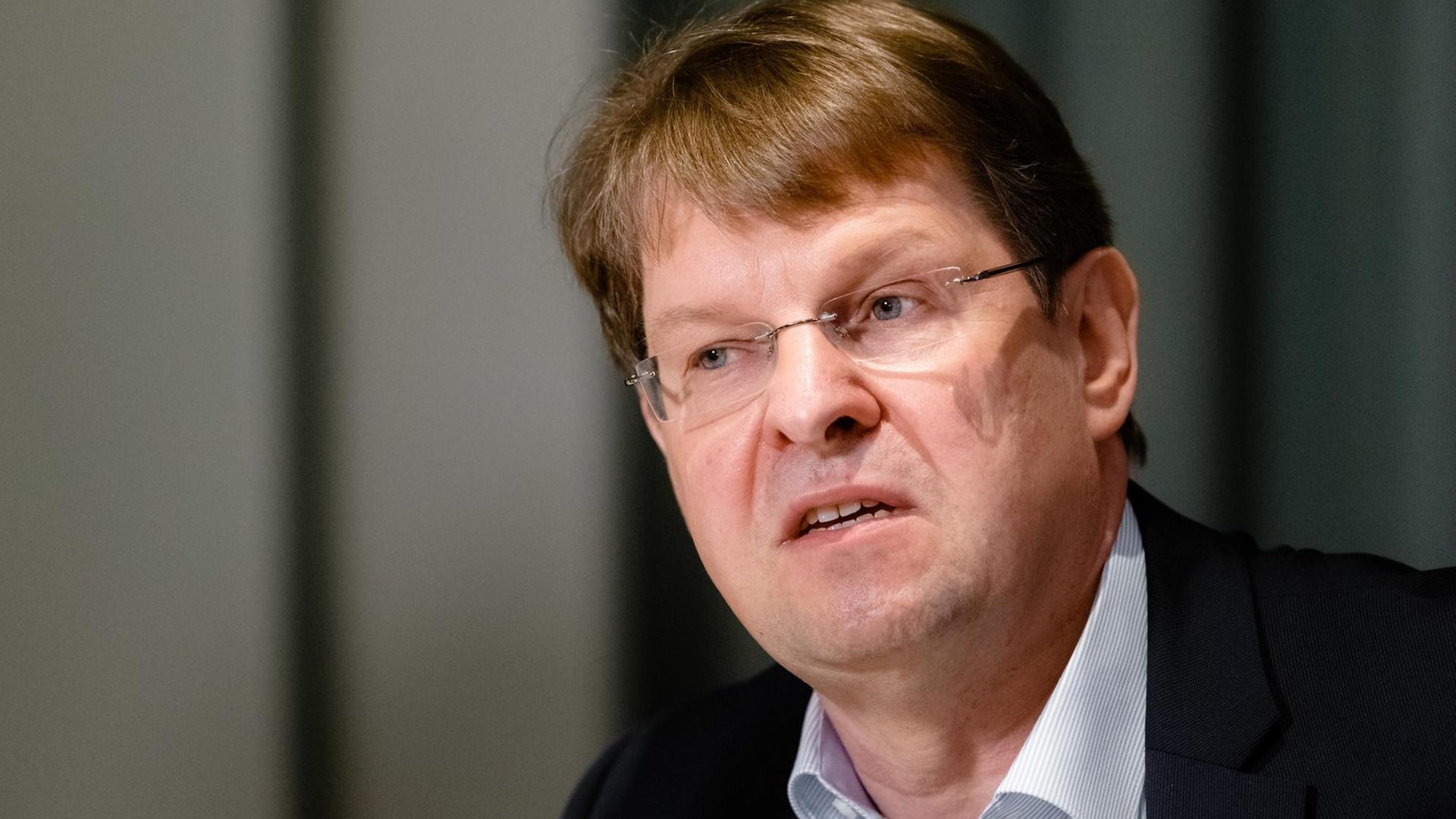 Mann in mittleren Jahren mit brauen Haaren und randloser Brille schaut nachdenklich nach links Mann in mittleren Jahren mit brauen Haaren und randloser Brille schaut nachdenklich nach links