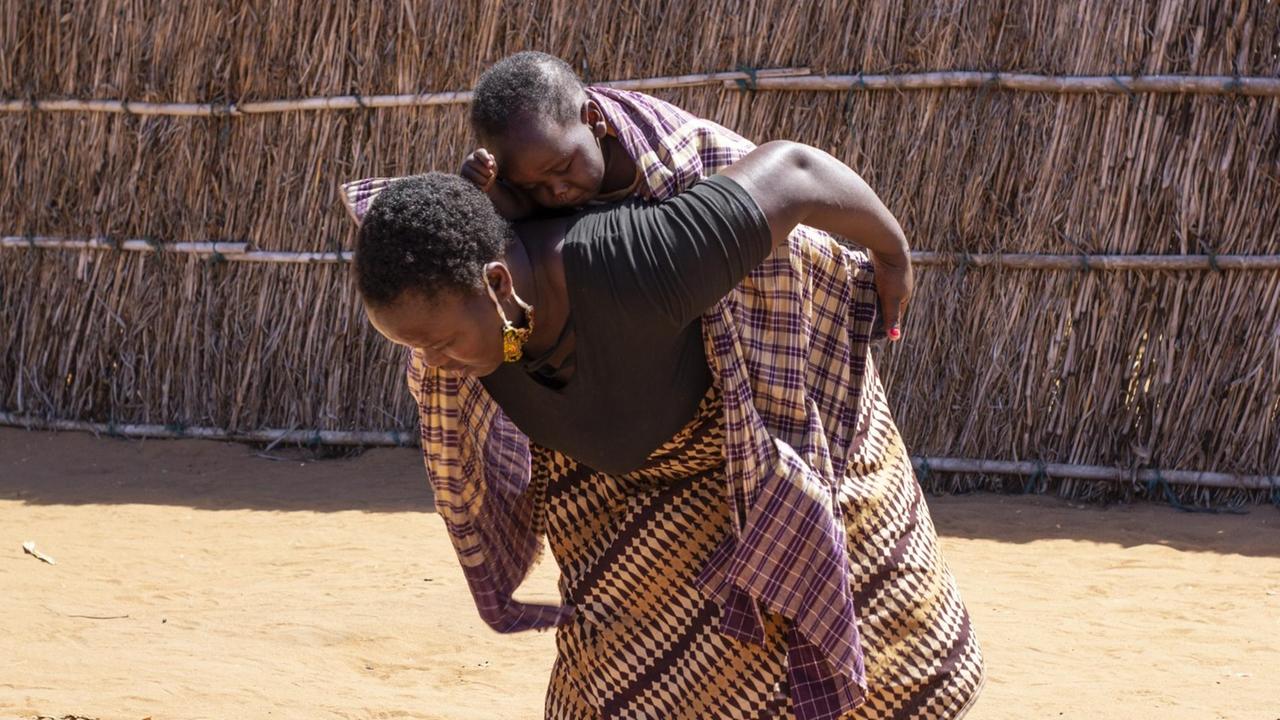 In this handout photo provided by the World Food Program on Tuesday, Sept. 22, 2020, a woman carries a child on her back after collecting a monthly food voucher in Cabo Delgado Province, Mozambique, Thursday, Aug. 27, 2020. The WFP says the escalating extremist insurgency in northern Mozambique has displaced 310,000 people, creating an urgent humanitarian crisis. (Falume Bachir/World Food Program via AP) In this handout photo provided by the World Food Program on Tuesday, Sept. 22, 2020, a woman carries a child on her back after collecting a monthly food voucher in Cabo Delgado Province, Mozambique, Thursday, Aug. 27, 2020. The WFP says the escalating extremist insurgency in northern Mozambique has displaced 310,000 people, creating an urgent humanitarian crisis. (Falume Bachir/World Food Program via AP)