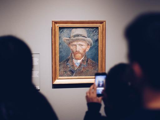 Ein Mann im Rijksmuseum in Amsterdam macht mit seinem Handy ein Foto von van Goghs Selbstporträt.