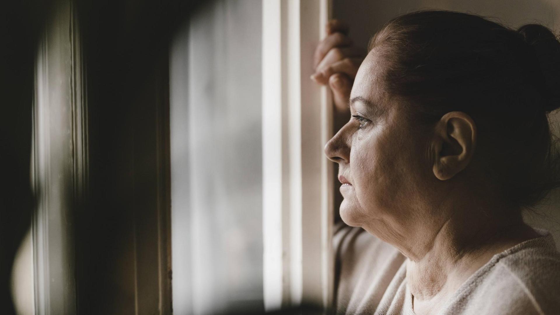 Eine ätere Frau schaut aus einem Fenster. Eine ätere Frau schaut aus einem Fenster.