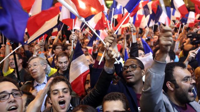 Unterstützer des französischen Präsidentschaftskandidaten Emmanuel Macron bejubeln in Paris mit französischen Flaggen die ersten Hochrechnungen.