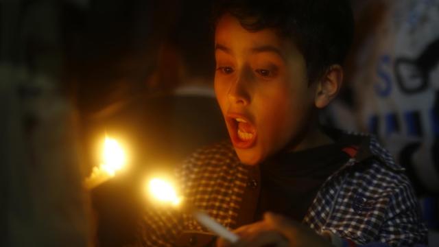 Ein palästinensisches Kind hält eine Kerze in der Hand.