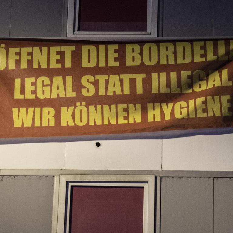 "Öffnet die Bordelle! Legal statt illegal - Wir können Hygiene" steht auf einem Banner an der Fassade eines geschlossenen Rotlicht-Etablissement im Bahnhofsviertel von Frankfurt. Seit einem Jahr sind auch in Hessen die regulären Bordelle von Corona-Verordnungen betroffen und sind geschlossen.