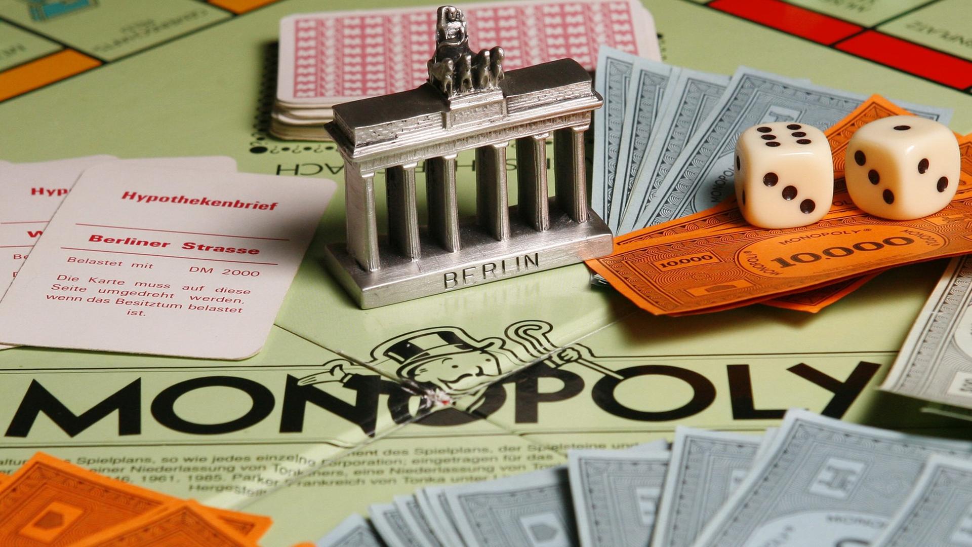 Ein Modell des Brandenburger Tores steht am Montag (02.04.2007) in Berlin auf einem Monopoly-Brettspiel inmitten von Karten, Würfeln und Spielgeld-Scheinen. Ein Modell des Brandenburger Tores steht am Montag (02.04.2007) in Berlin auf einem Monopoly-Brettspiel inmitten von Karten, Würfeln und Spielgeld-Scheinen.
