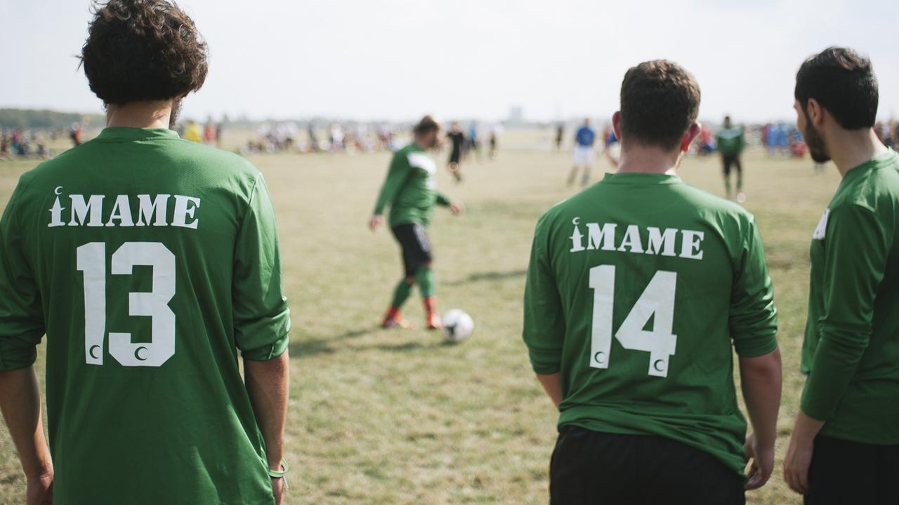 Männer in Trikots, auf denen "Imame" zu lesen ist beim Fußballturnier "Imame gegen Pfarrer" in Berlin.