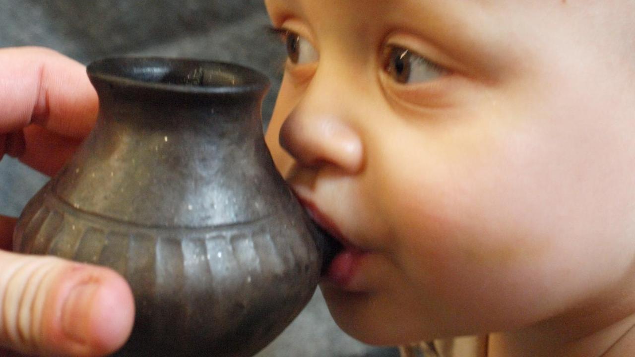 Ein Baby wird mit Hilfe der Rekonstruktion eines prähistorischen "Fläschchens" gefüttert. Ein Baby wird mit Hilfe der Rekonstruktion eines prähistorischen "Fläschchens" gefüttert.