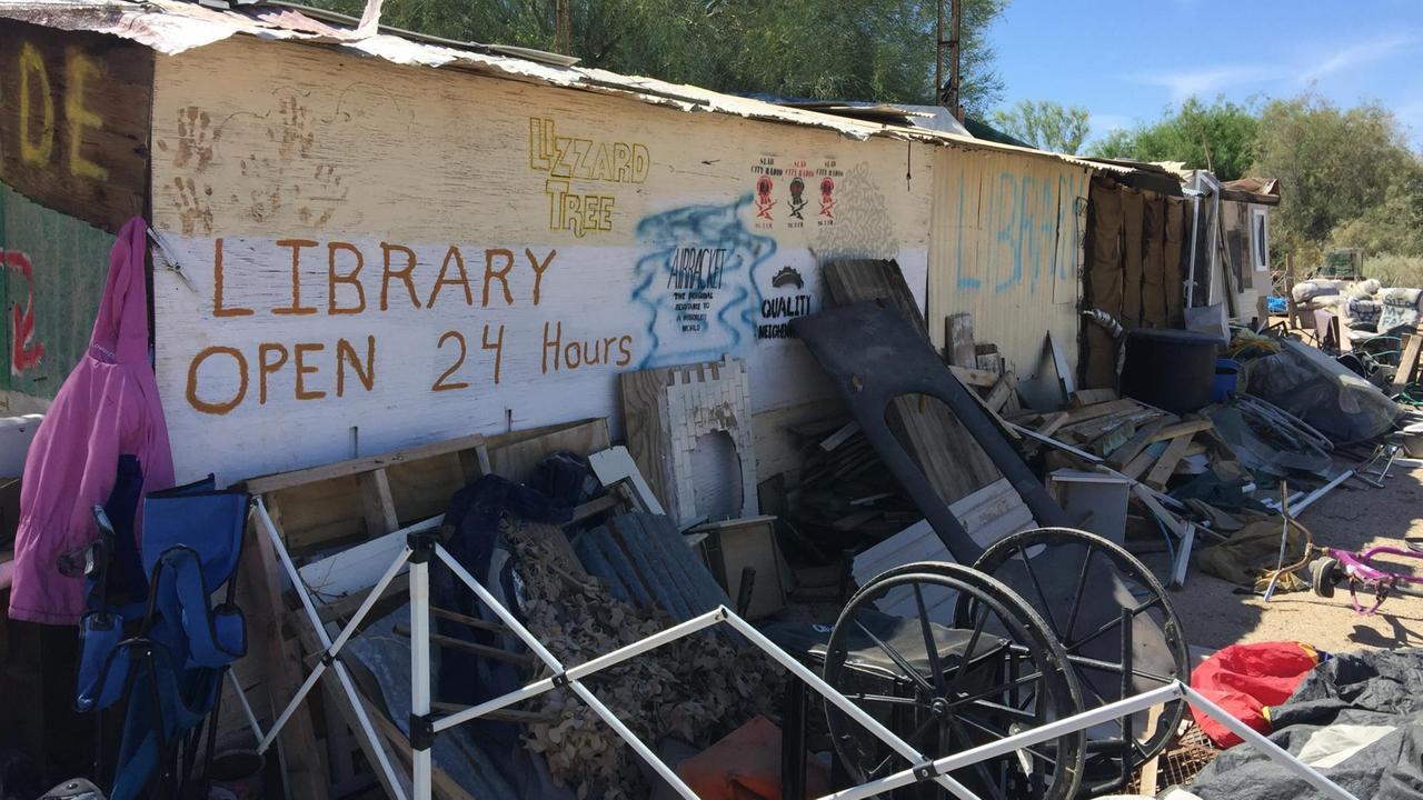 Eine Bretterbude dient als Bibliothek von Slab Citiy. Viel Gerümpel steht davor. Eine Bretterbude dient als Bibliothek von Slab Citiy. Viel Gerümpel steht davor.