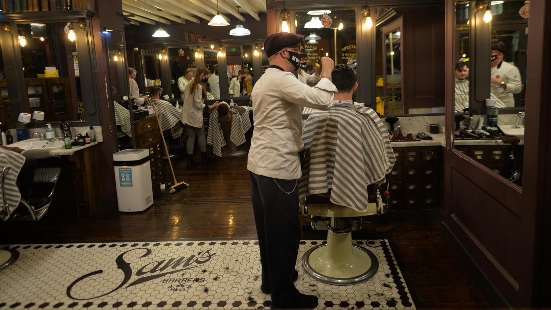 Ein Friseur mit Maske schneidet einem Kunden die Haare. Ein Friseur mit Maske schneidet einem Kunden die Haare.