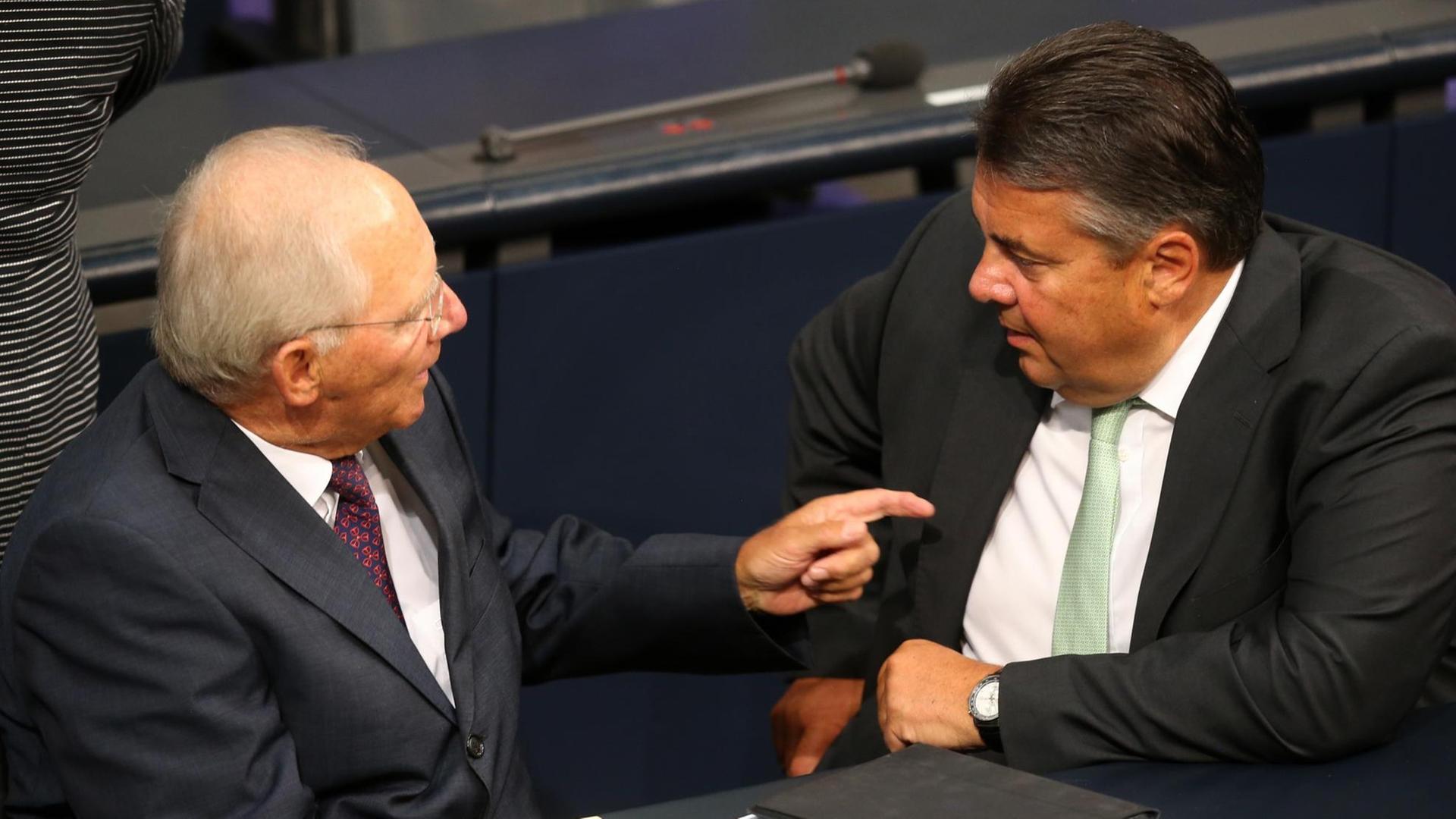 Finanzminister Wollfgang Schäuble (CDU, l) und Wirtschaftsminister Sigmar Gabriel (SPD) unterhalten sich im Bundestag